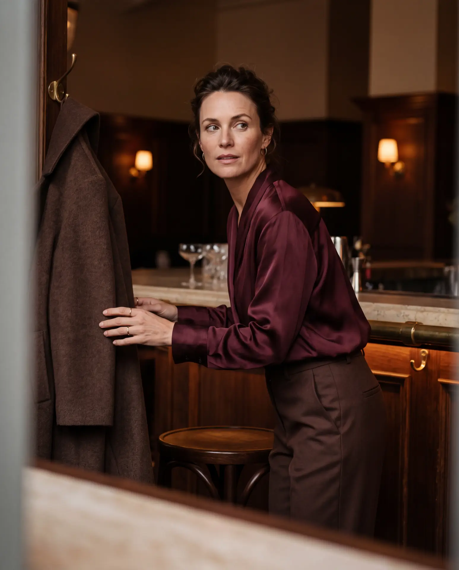 A woman in a satin blouse at an evening bar, glancing over her shoulder